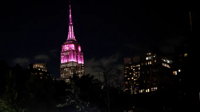 Empire State Building lit pink at night against the Manhattan skyline Keyword: commercial real estate