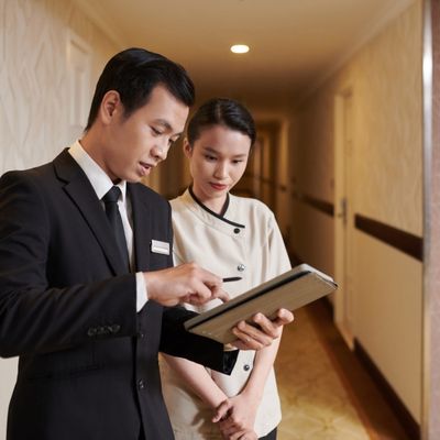 hotel concierge showing a staff member plans for hospitality development on a tablet